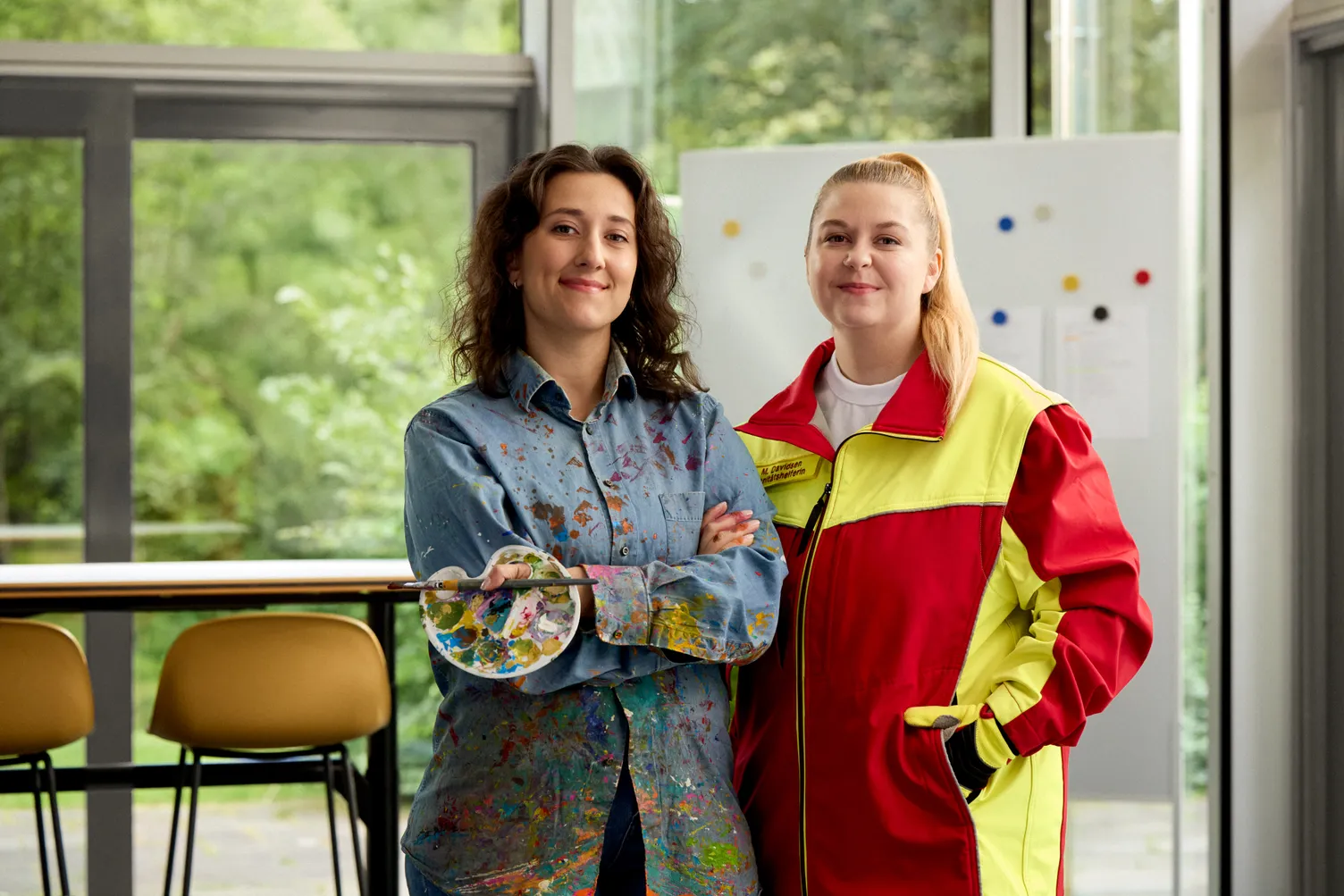 Gruppenfoto mit Sahra Jabari in Malerkittel und Monique Davidsen in Katastrophenschutz-Uniform